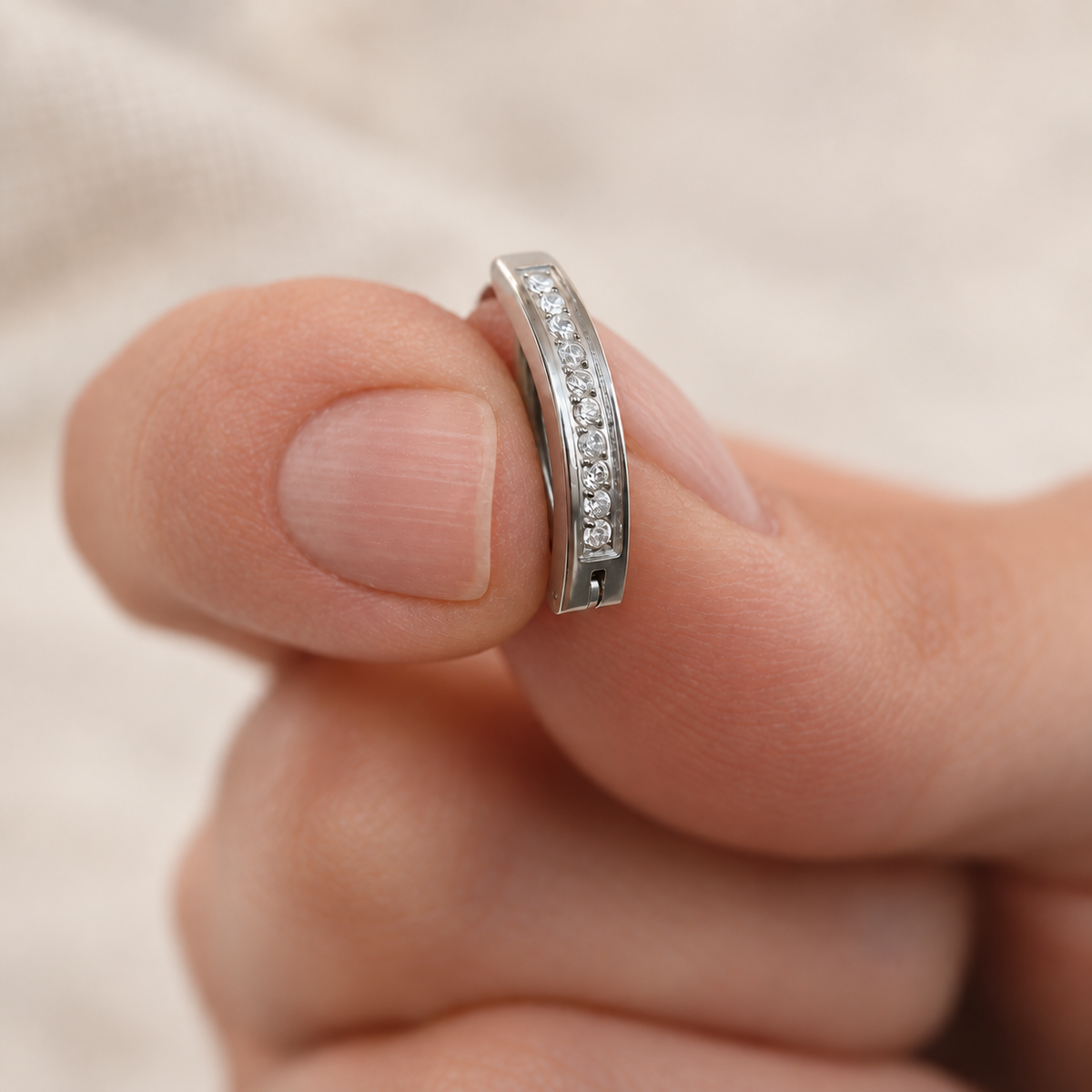 Silver-tone curved belly jewellery with clear stones - held between fingers
