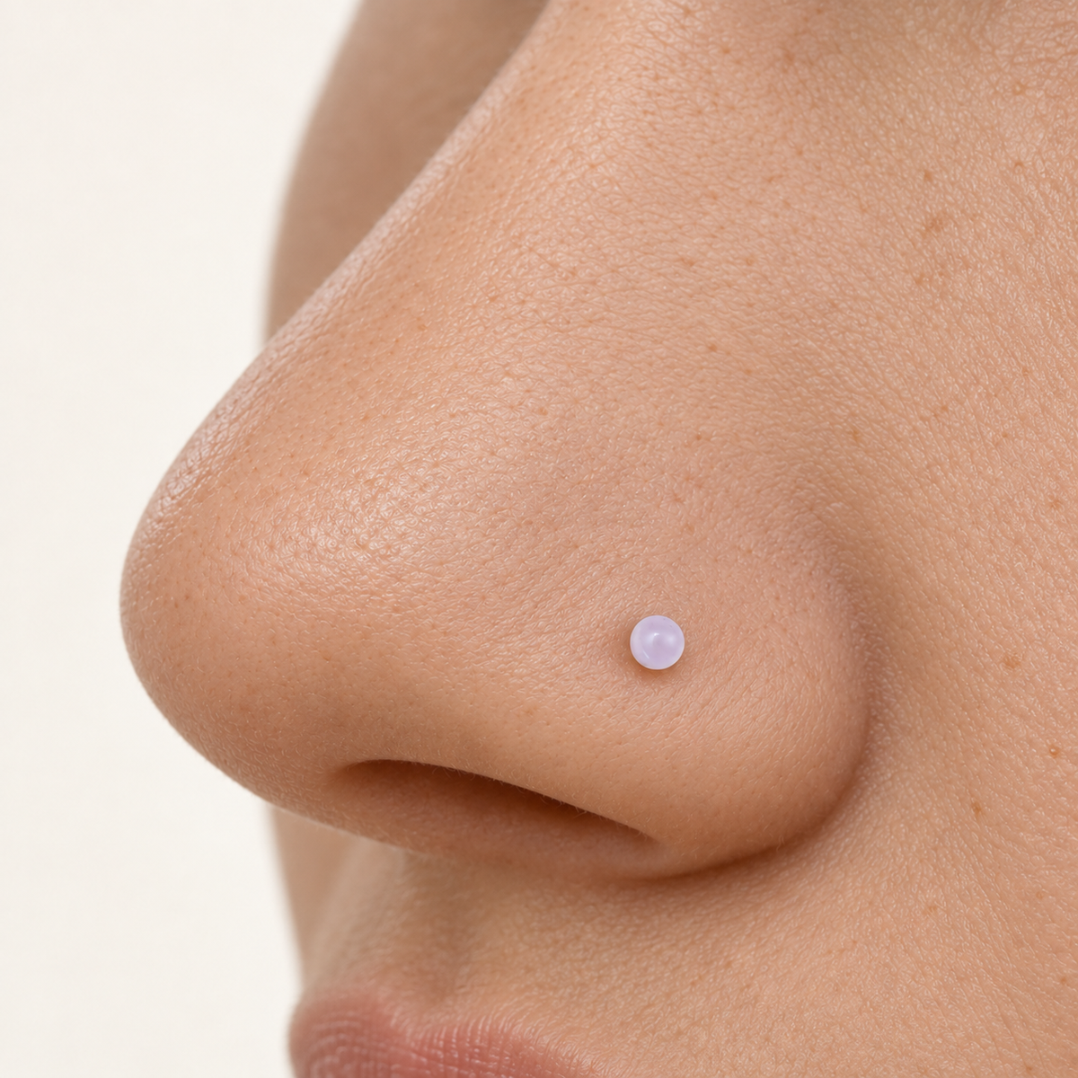 Clear nose stud retainer worn in a nostril piercing
