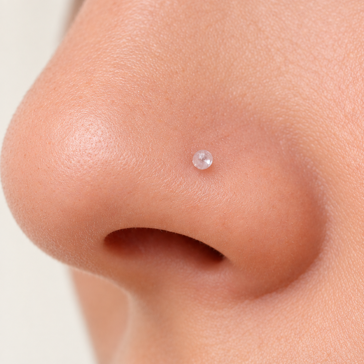 Clear nose stud retainer worn in a nostril piercing