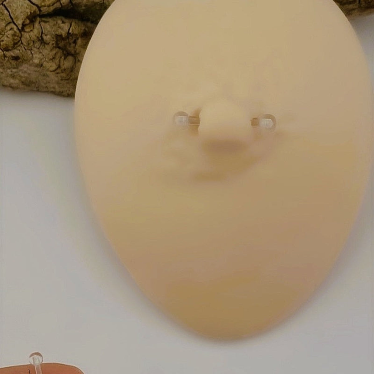 Clear nipple retainer displayed on a silicone demonstration model
