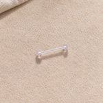 Clear nipple retainer barbell on a neutral textured surface