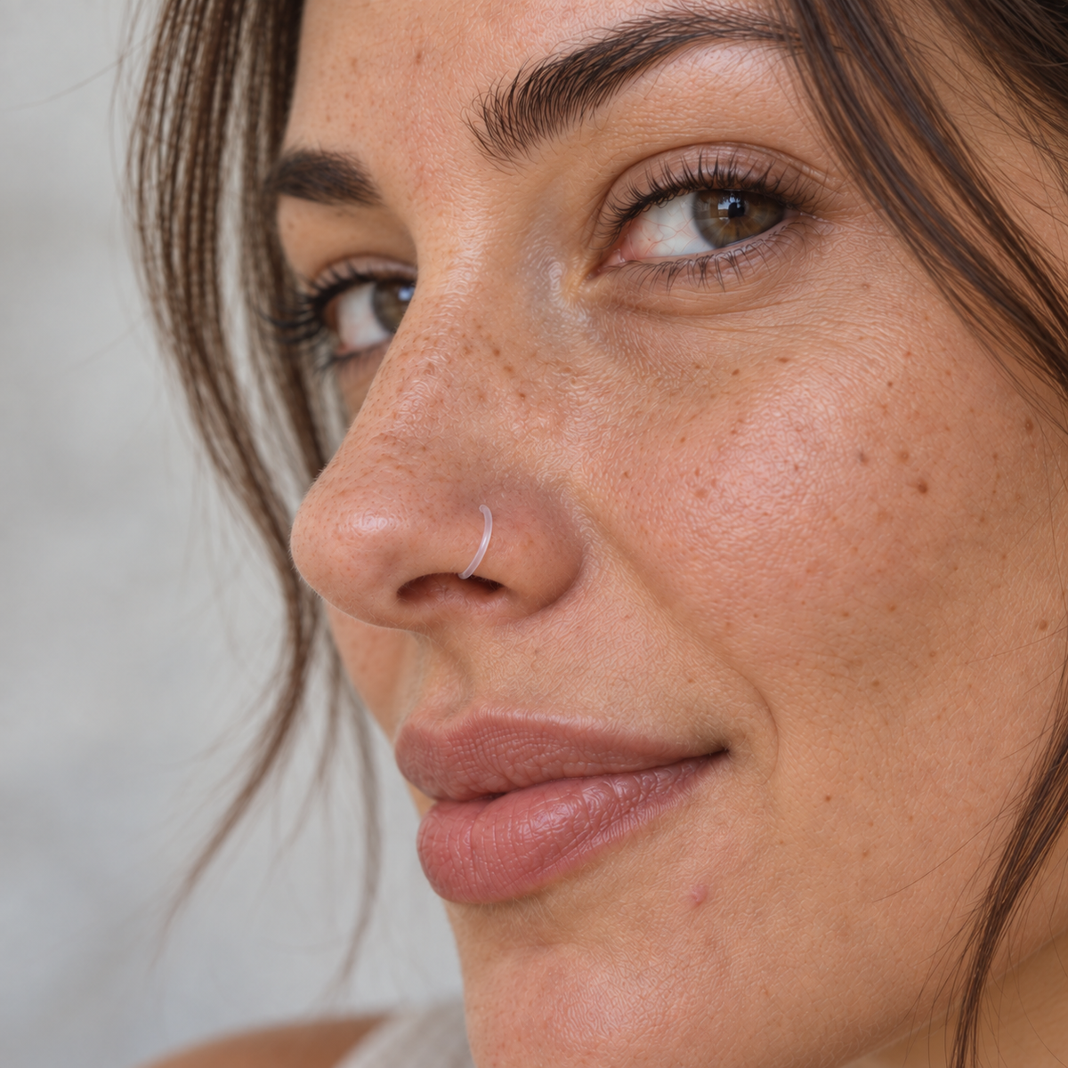 Clear nose ring retainer worn in the nostril, close-up