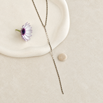 Silver disc lariat necklace displayed on cream background