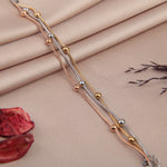 Set of three beaded bracelets in gold, silver and rose gold tones on a fabric background