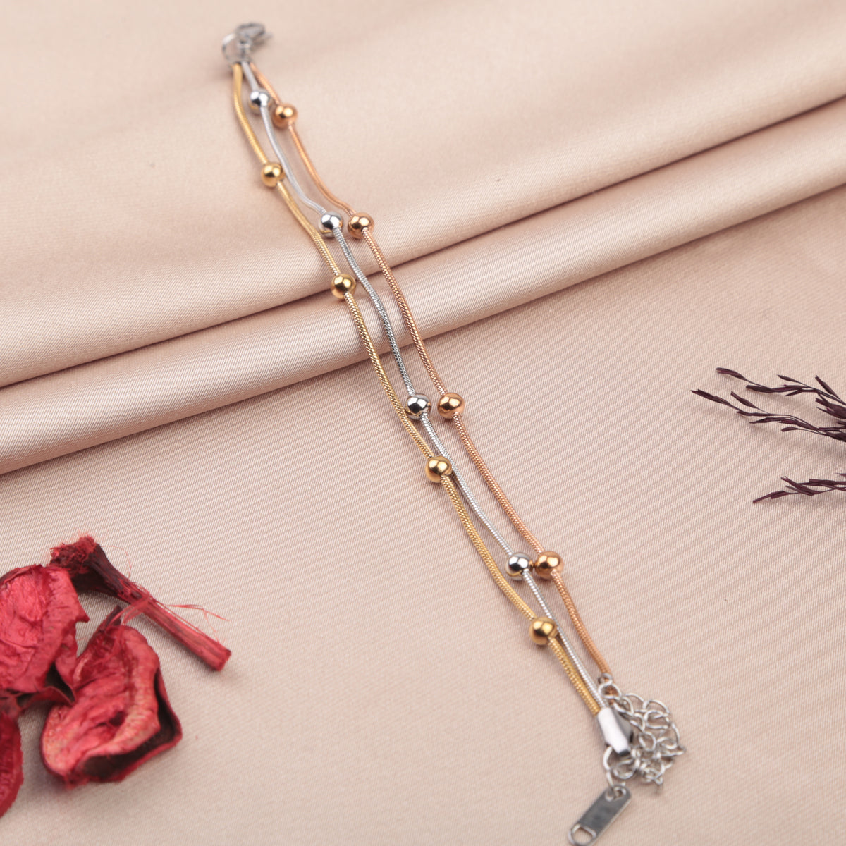 Set of three beaded bracelets in gold, silver and rose gold tones on a fabric background