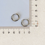 Two silver-tone hoops shown from the back beside rulers, with the backs of their round stone settings visible.