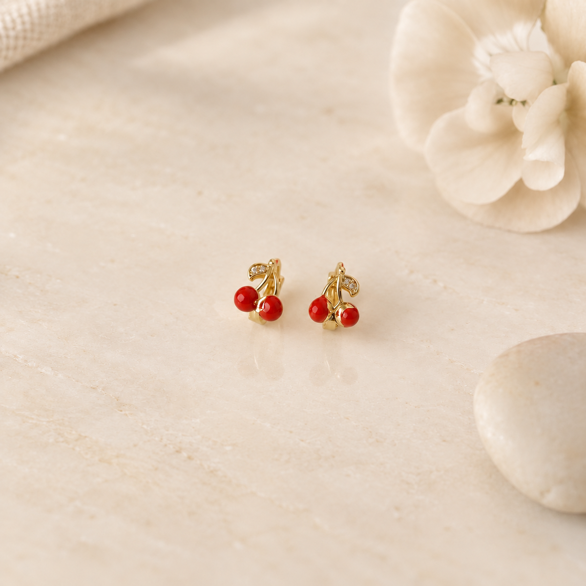 Pair of gold-tone cherry earrings with red cherries and green leaves, front view — Toku LONDON
