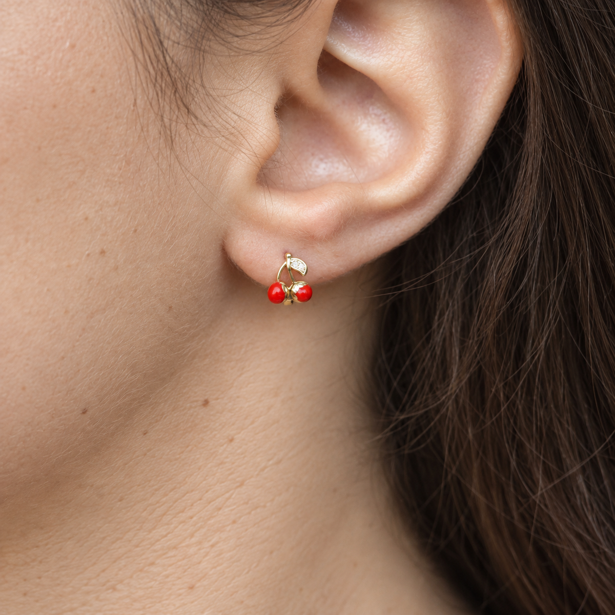 Close-up of a red cherry earring worn on the ear — Toku LONDON