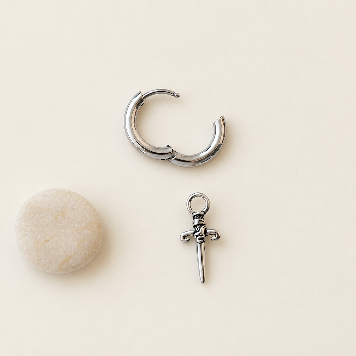 Silver dagger charm hoop earring, open clasp and charm detail