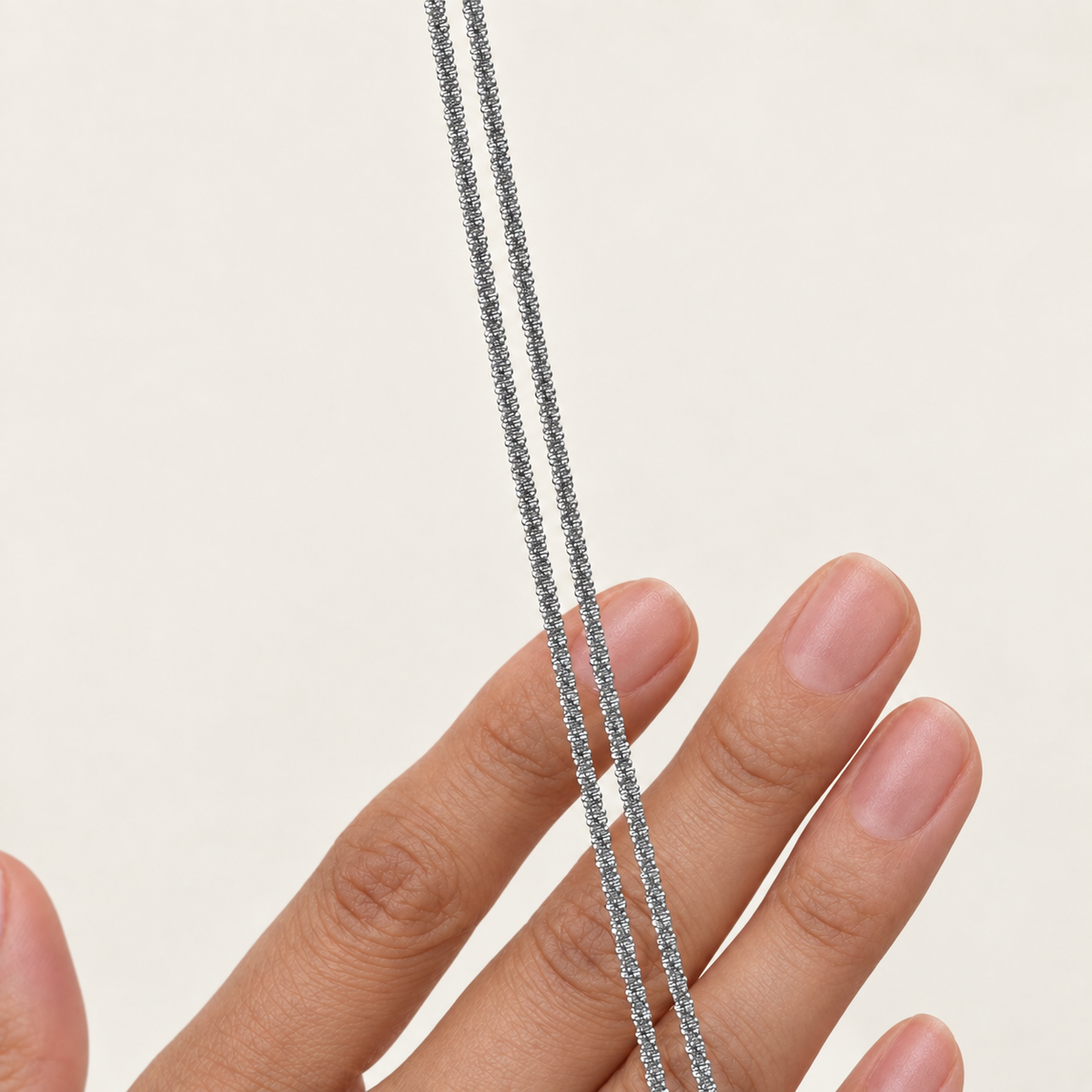 Silver glitter chain necklace draped over a hand