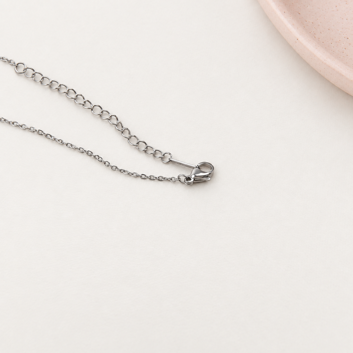 Detail of the lobster clasp and extension chain on a silver glitter necklace