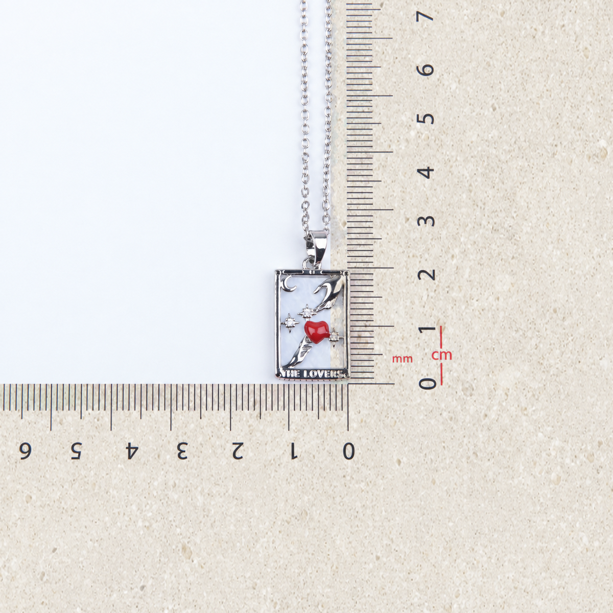 Lovers tarot pendant beside a ruler for size reference