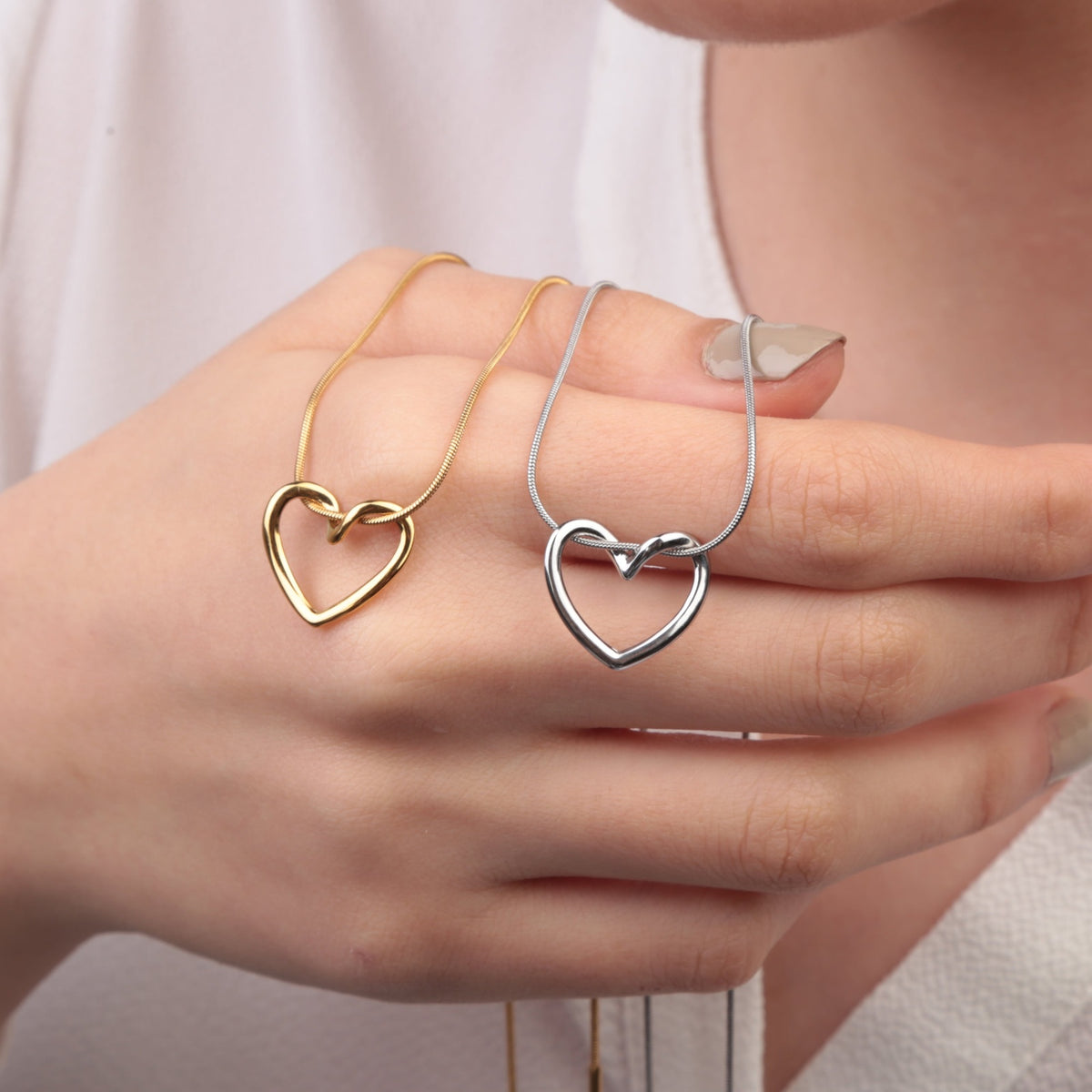 Gold and silver heart pendant necklace - held in hand