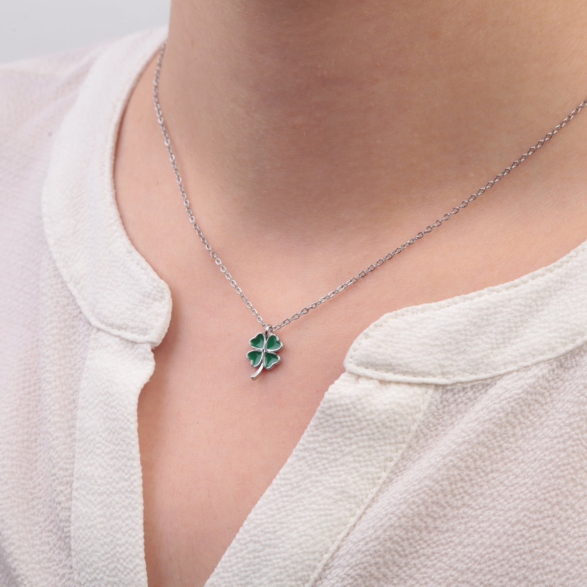 Silver green clover pendant necklace worn with white top