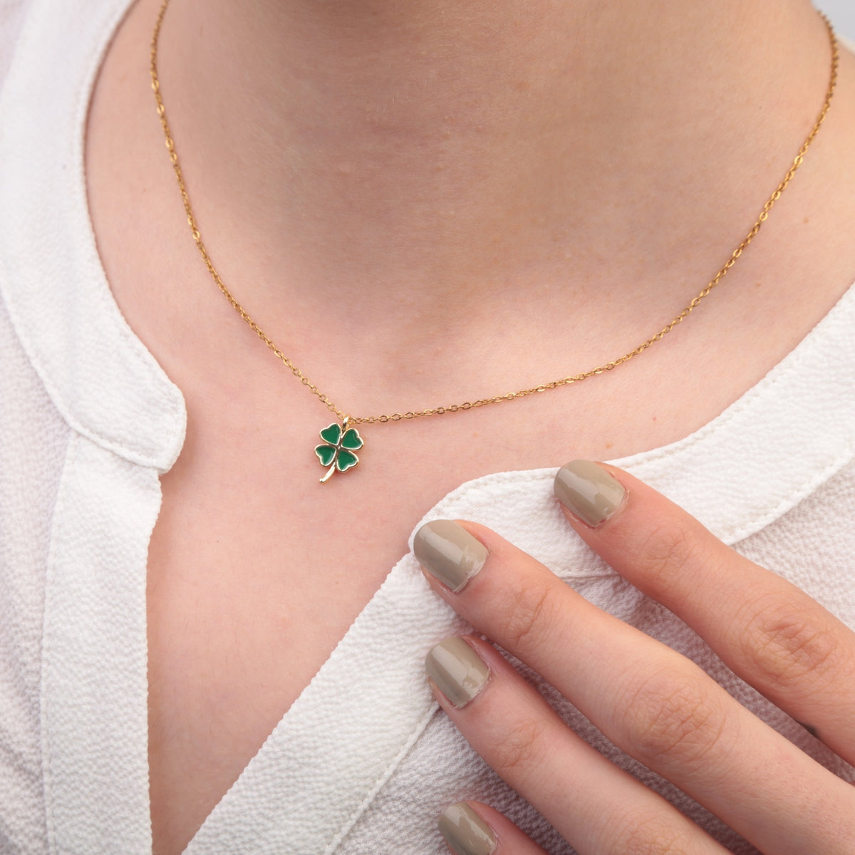 Gold clover necklace worn with white top