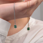 Gold and silver clover pendant necklaces held side by side