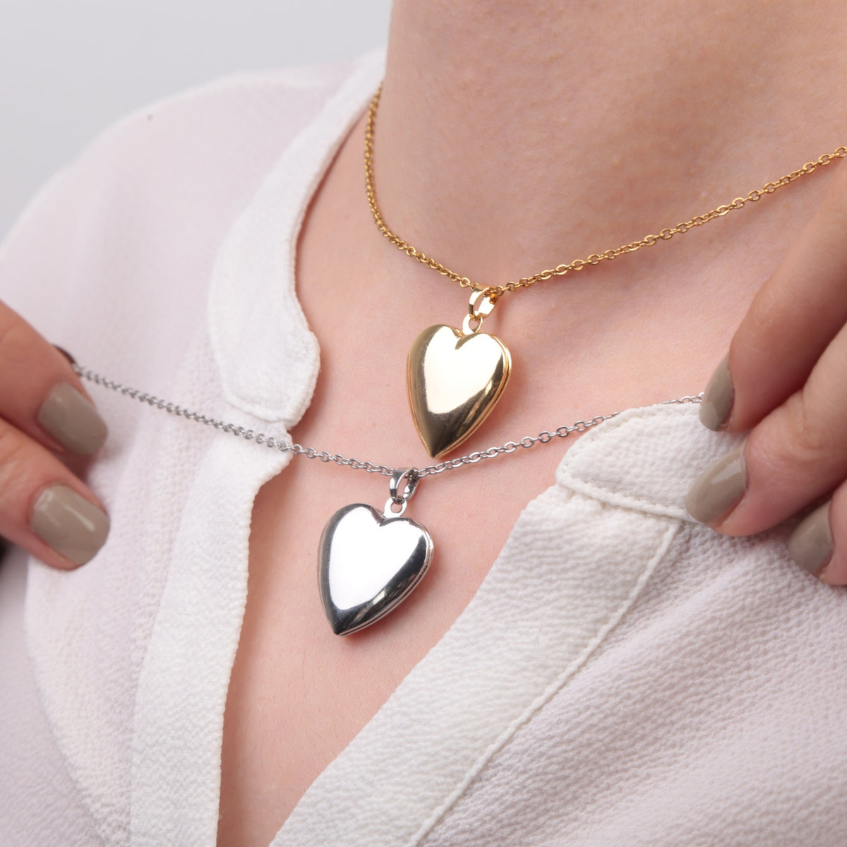 Gold and silver heart photo locket necklaces shown together on a model