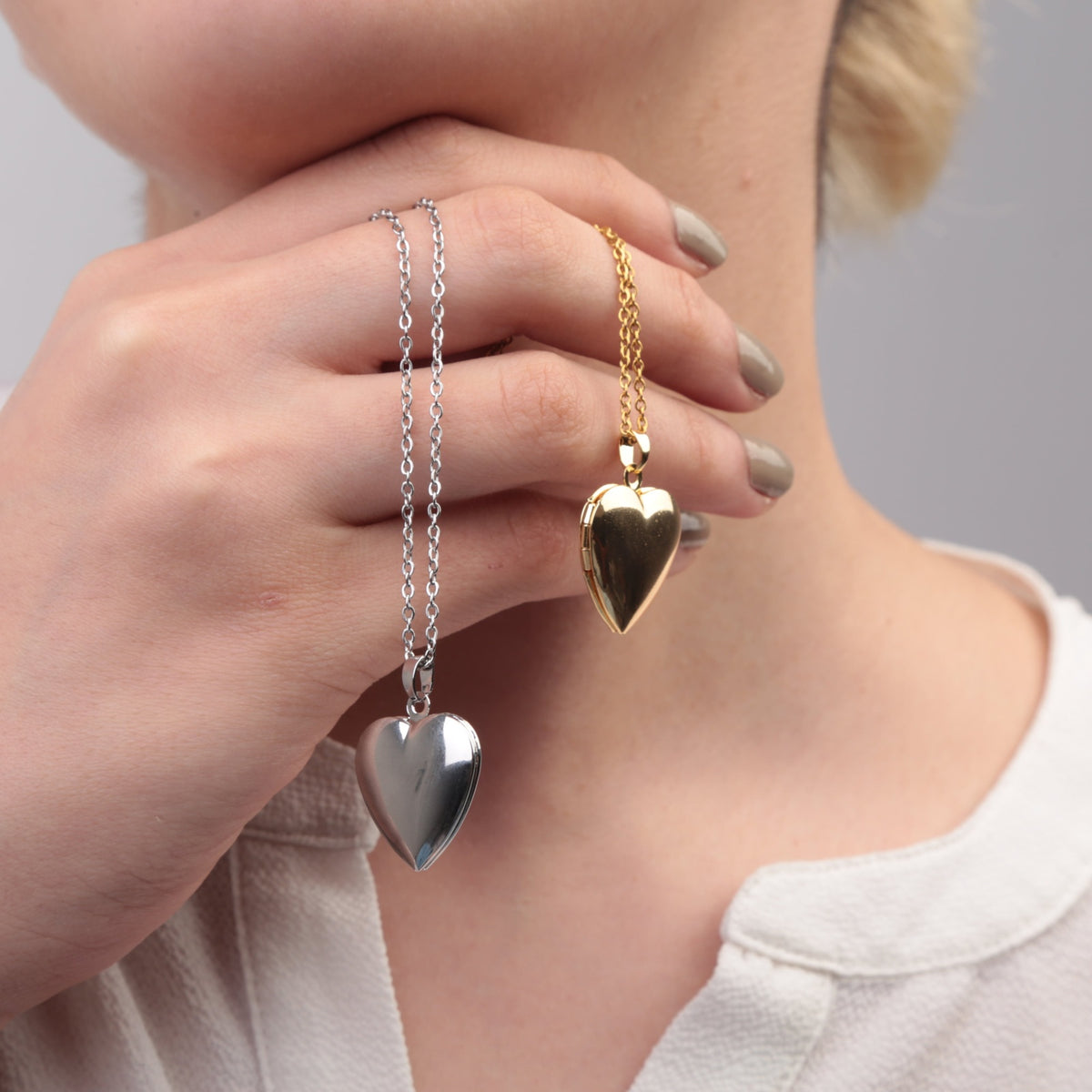 Gold and silver heart photo locket necklaces held for detail