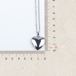 Heart photo locket pendant beside a ruler for size reference