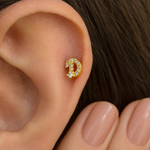 Gold zircon letter D piercing stud shown on the ear