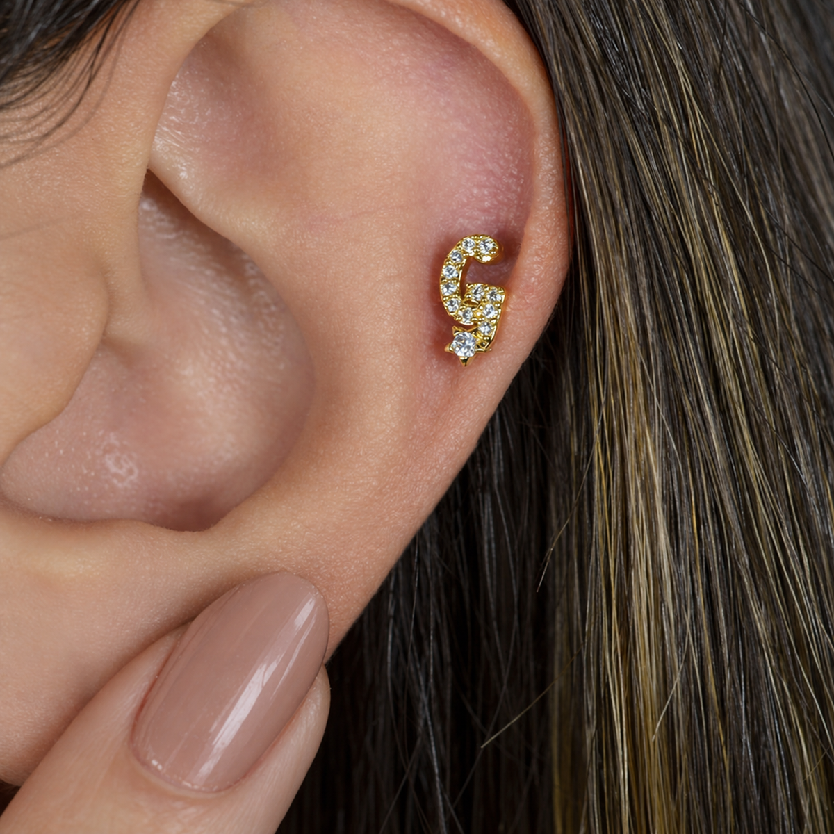 Gold zircon letter G piercing stud shown on the ear