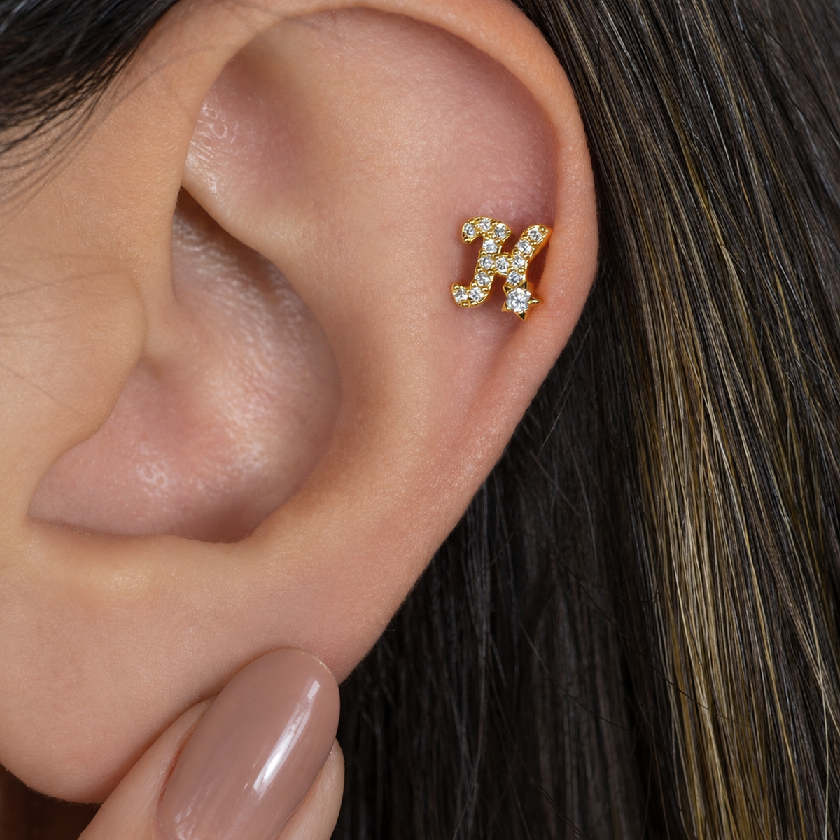 Gold zircon letter H piercing stud shown on the ear
