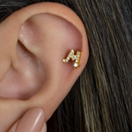 Gold zircon letter M piercing stud shown on the ear