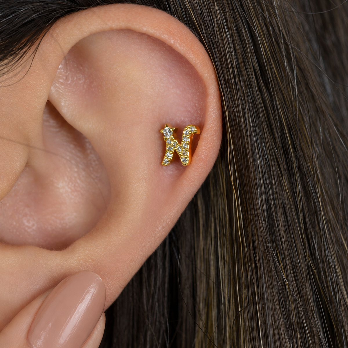 Gold zircon letter N piercing stud shown on the ear