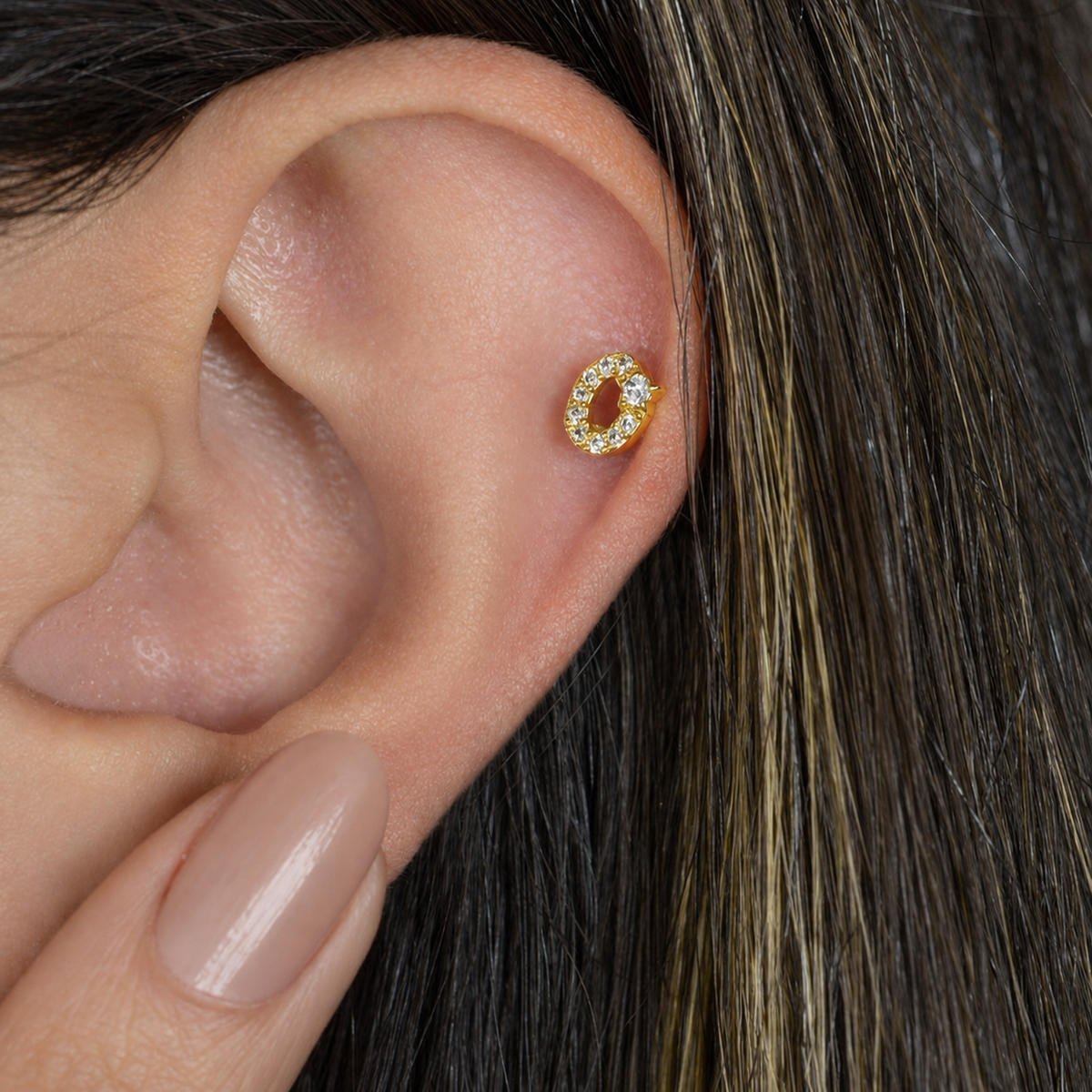 Gold zircon letter O piercing stud shown on the ear