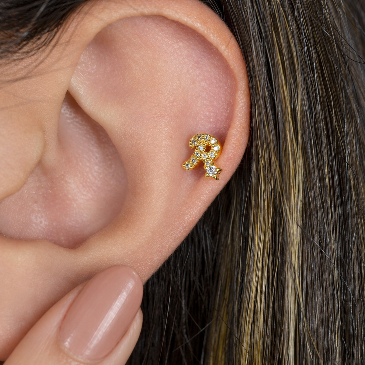 Gold zircon letter R piercing stud shown on the ear