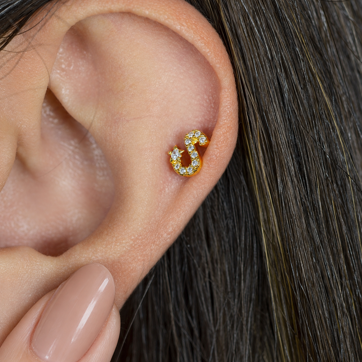 Gold zircon letter S piercing stud shown on the ear