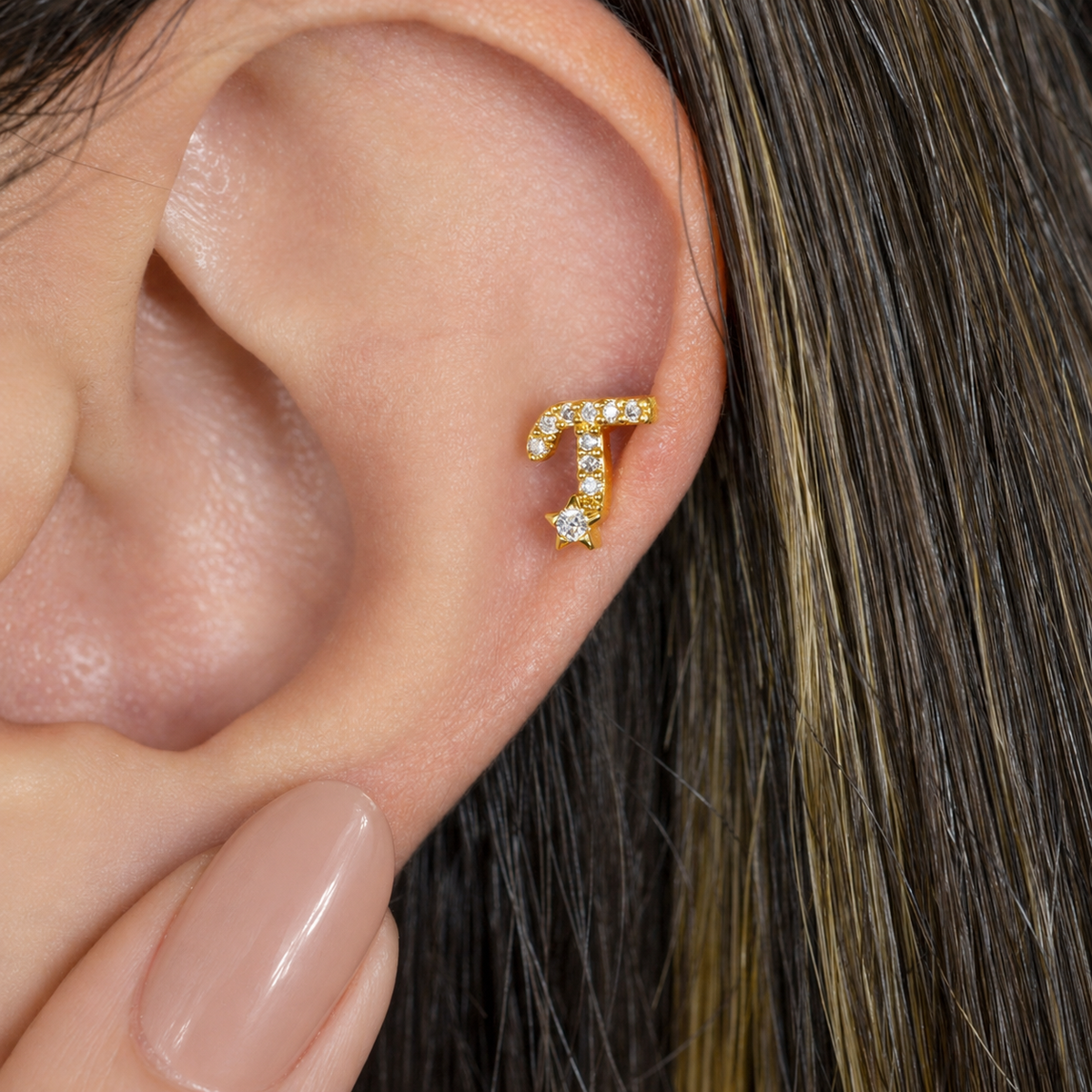 Gold zircon letter T piercing stud shown on the ear