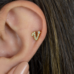 Gold zircon letter V piercing stud shown on the ear