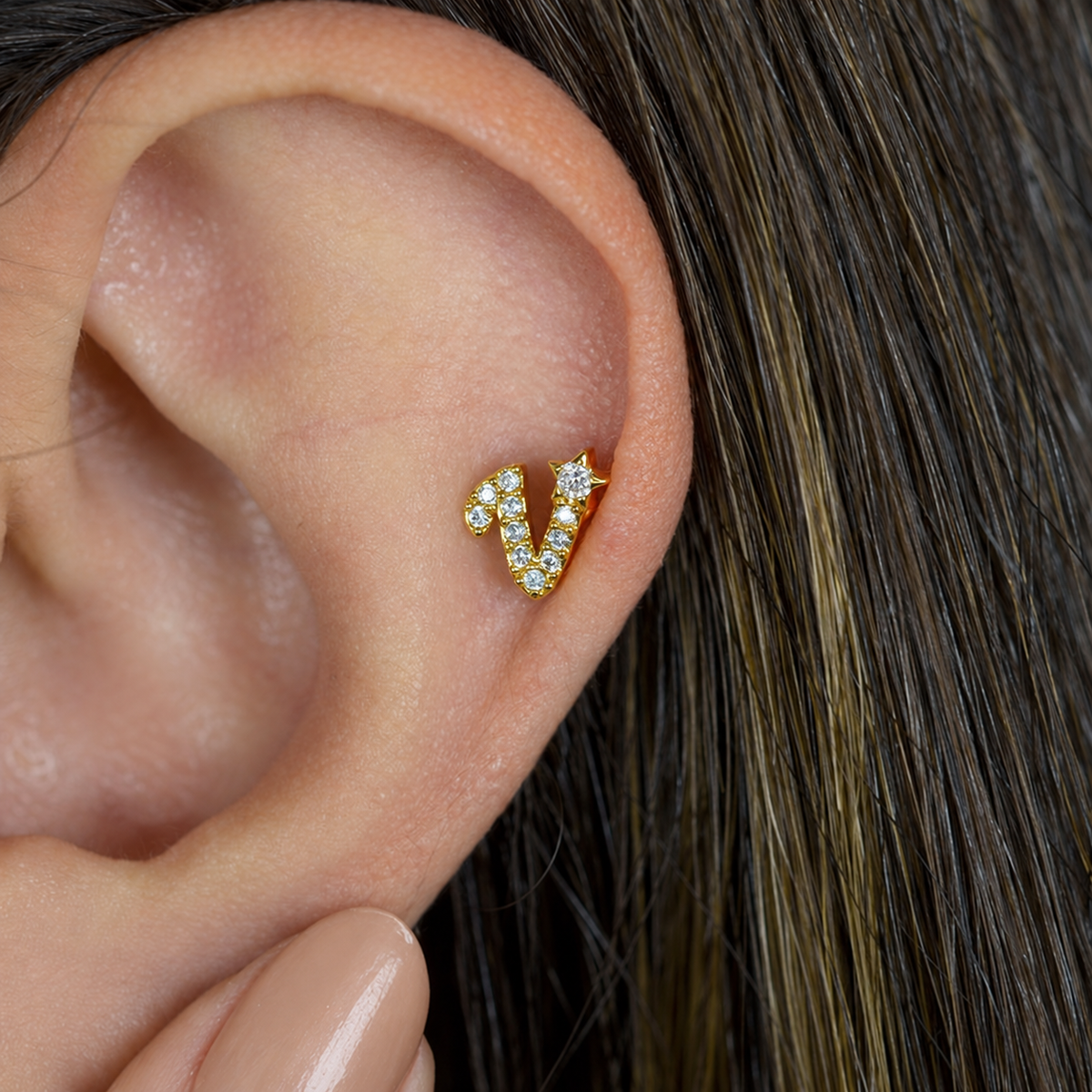 Gold zircon letter V piercing stud shown on the ear