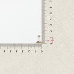 Gold zircon initial piercing stud beside a ruler for size reference