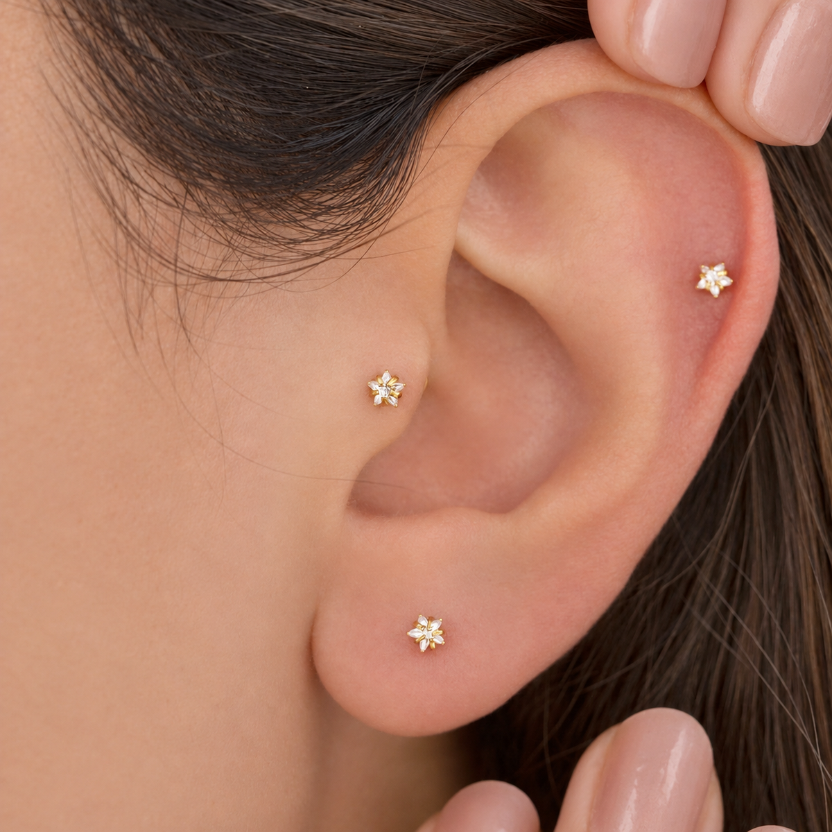 Gold star studs worn in ear piercings