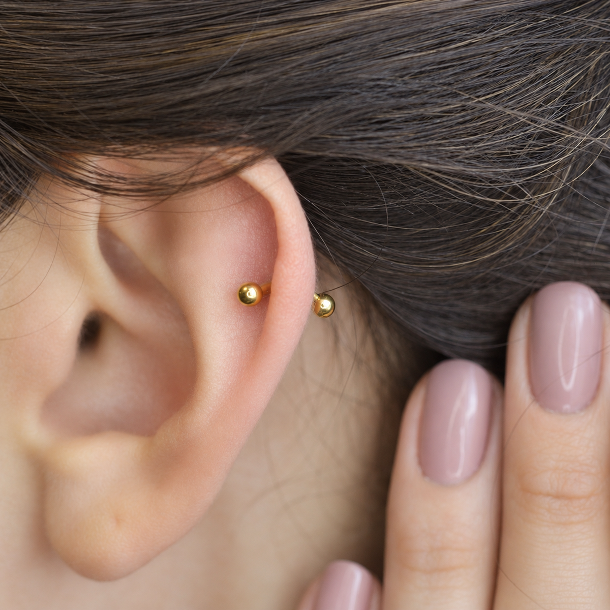 Gold curved barbell shown on the ear, side view