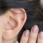 Gold curved barbell shown on the ear, front view