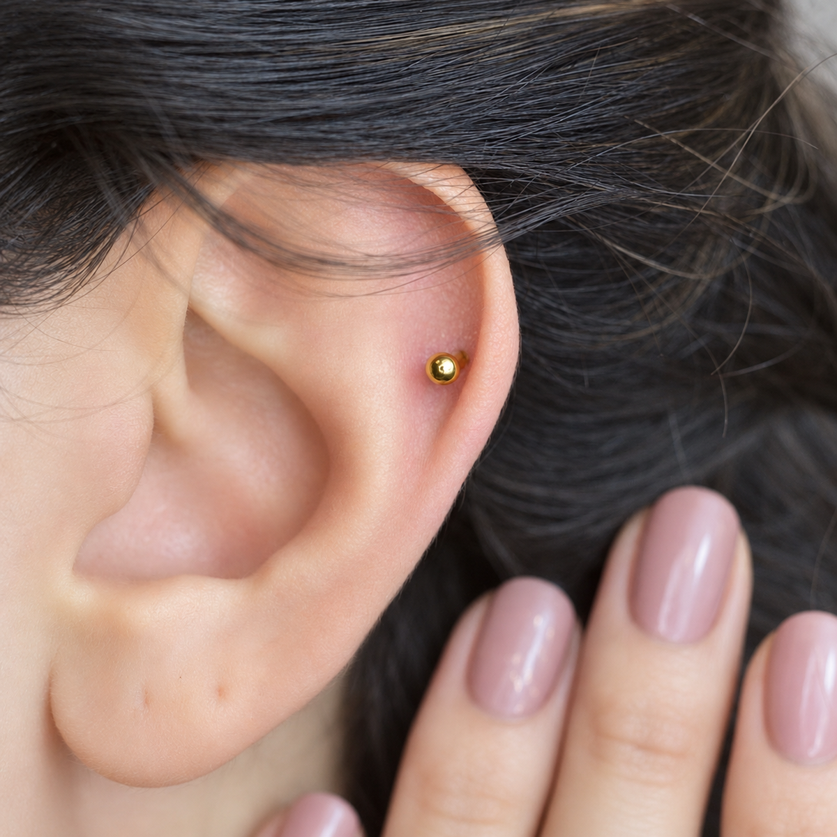 Gold curved barbell shown on the ear, front view