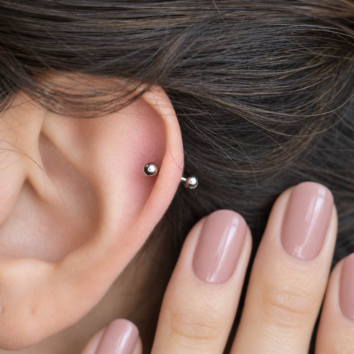 Silver curved barbell shown on the ear, side view