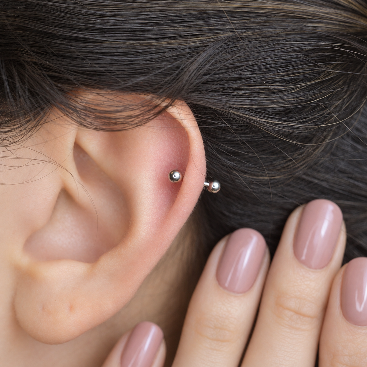 Silver curved barbell shown on the ear, front view