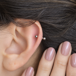 Silver curved barbell shown on the ear, front view