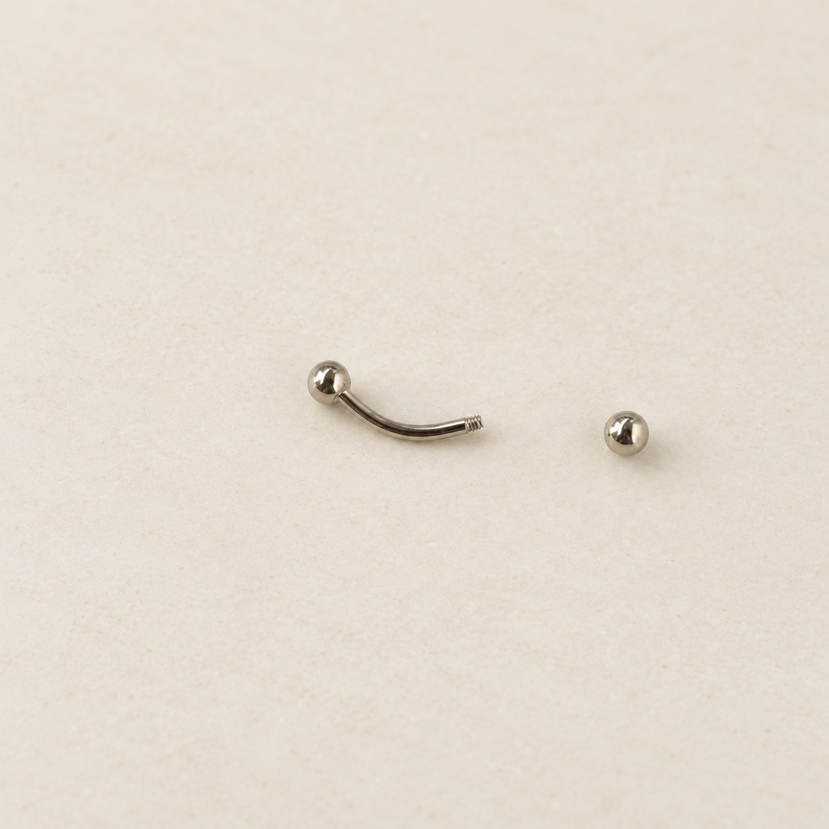 Silver curved barbell with one ball end removed