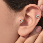 Silver zircon heart piercing studs shown on the ear