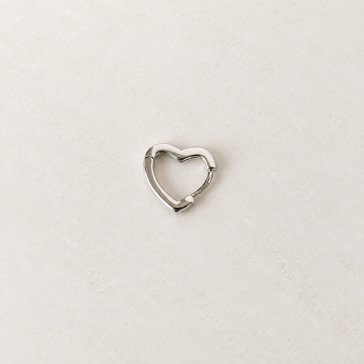 Silver heart-shaped hoop earring, product view — Toku LONDON