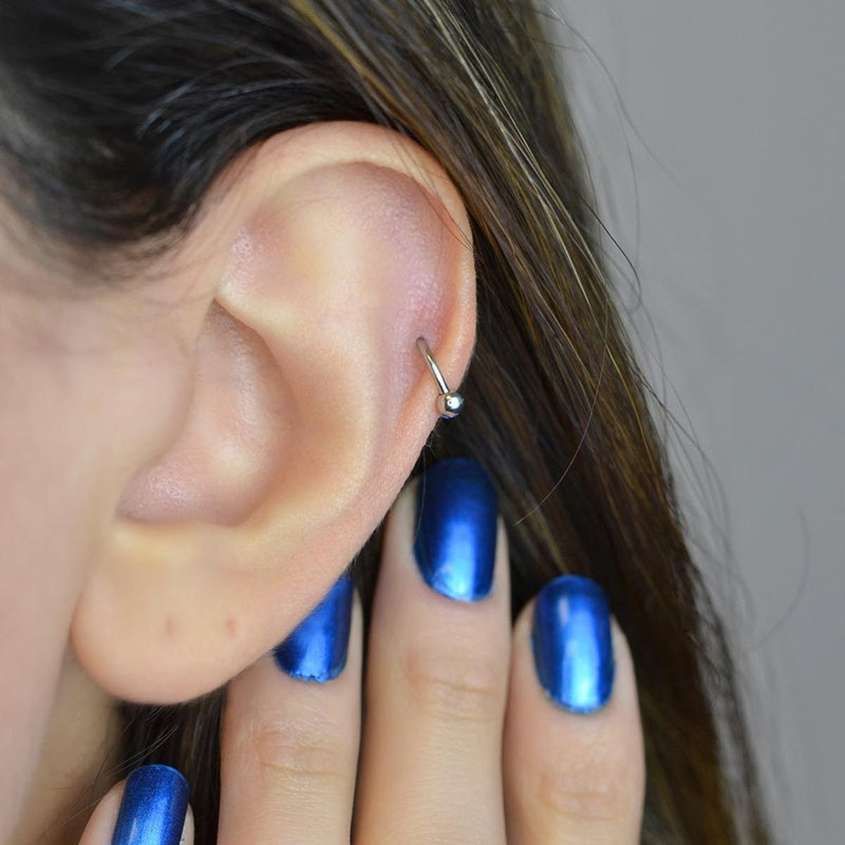 Silver horseshoe barbell worn on the ear