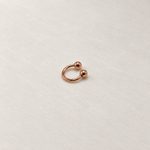 Rose gold ball-end horseshoe barbell on a neutral background