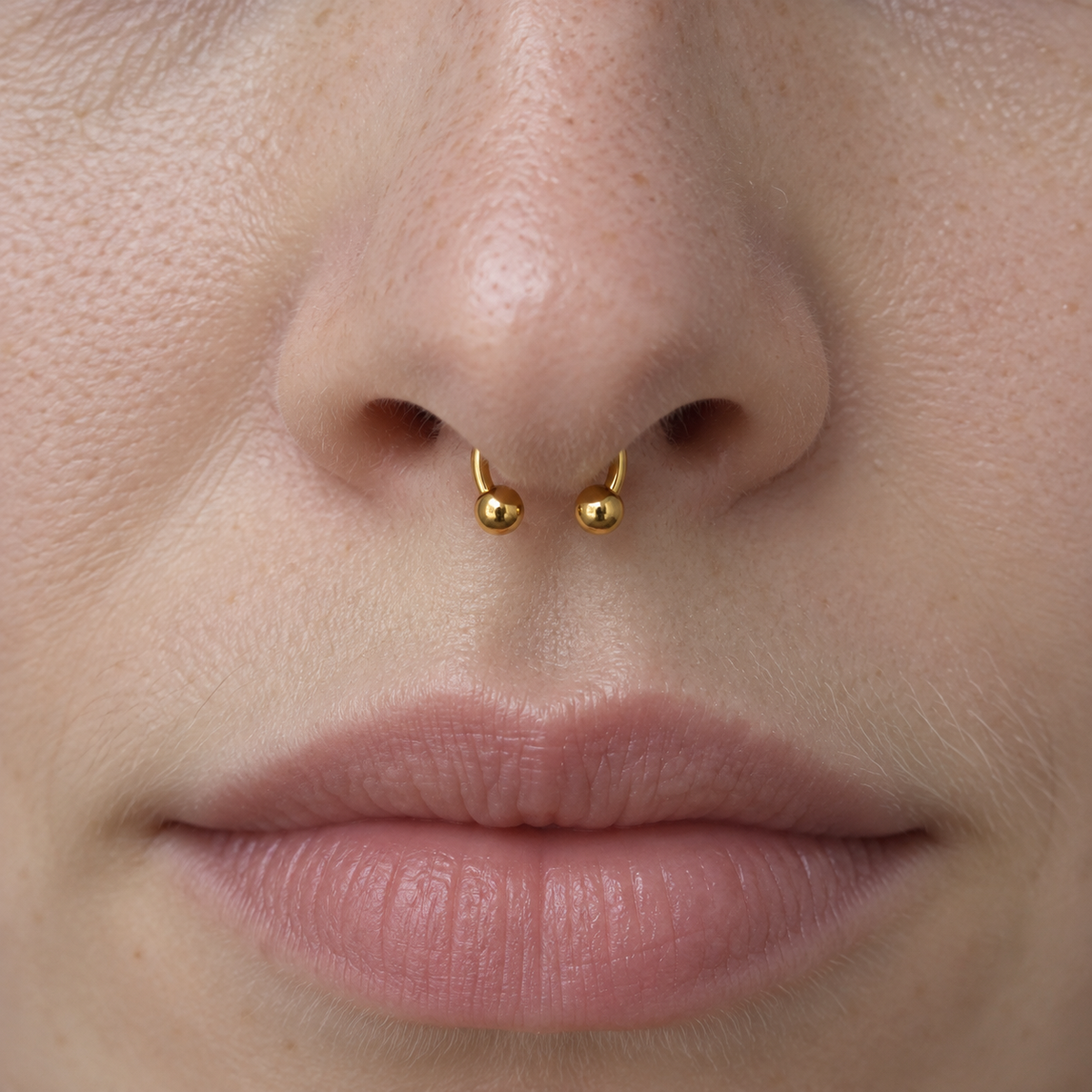 Gold horseshoe barbell worn in a septum piercing