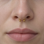 Gold horseshoe barbell worn in a septum piercing