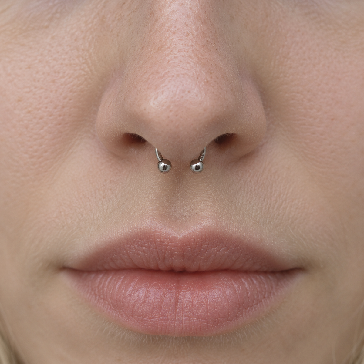 Silver horseshoe barbell worn in a septum piercing